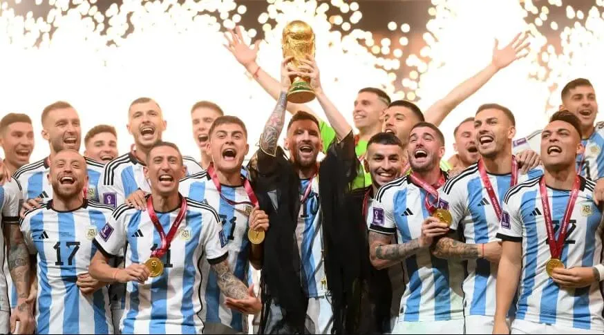 Comemoração da seleção argentina com Messi erguendo troféu com roupa típica