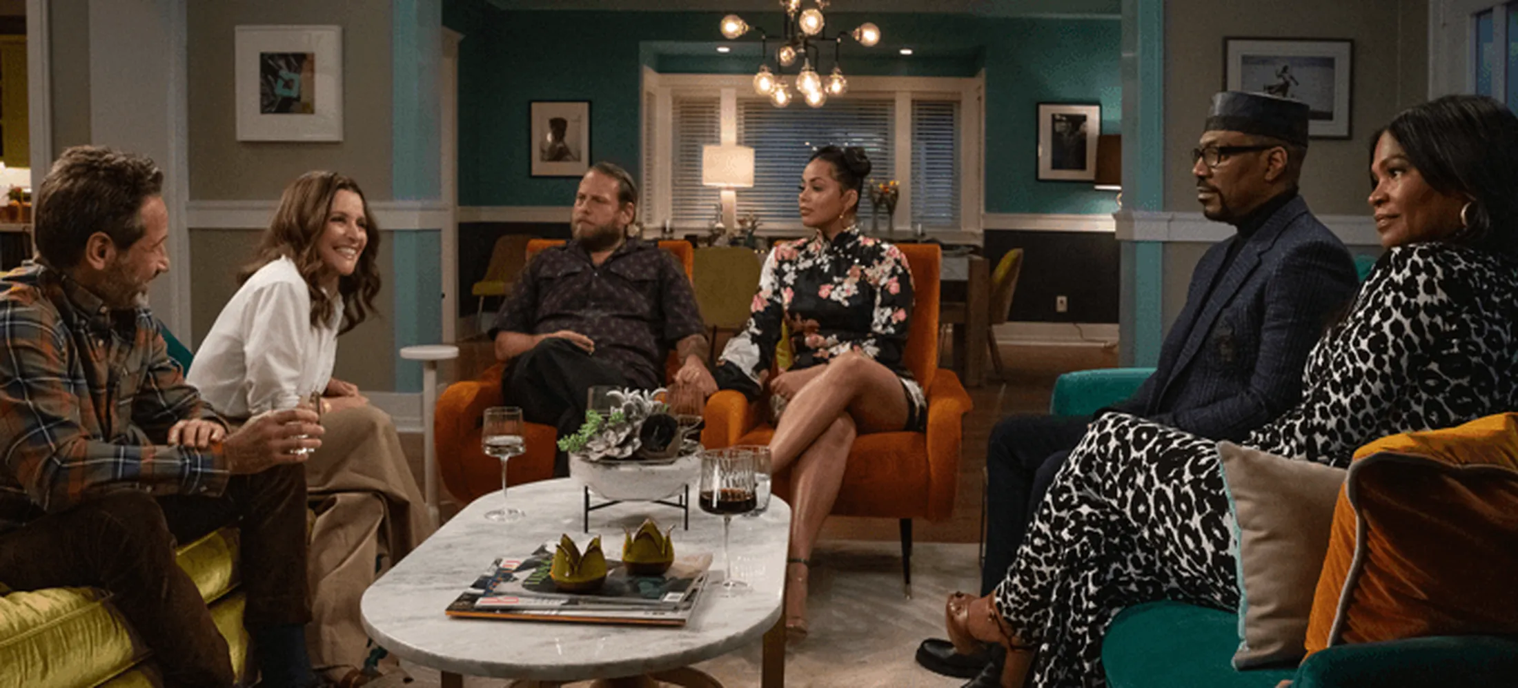 Personagens do filme sentados em uma sala de estar dialogando