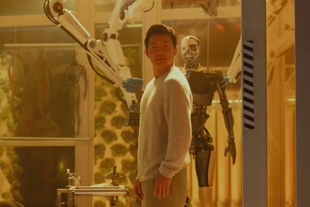 Imagem do ator Simu Liu com um robo atrás olhando para frente