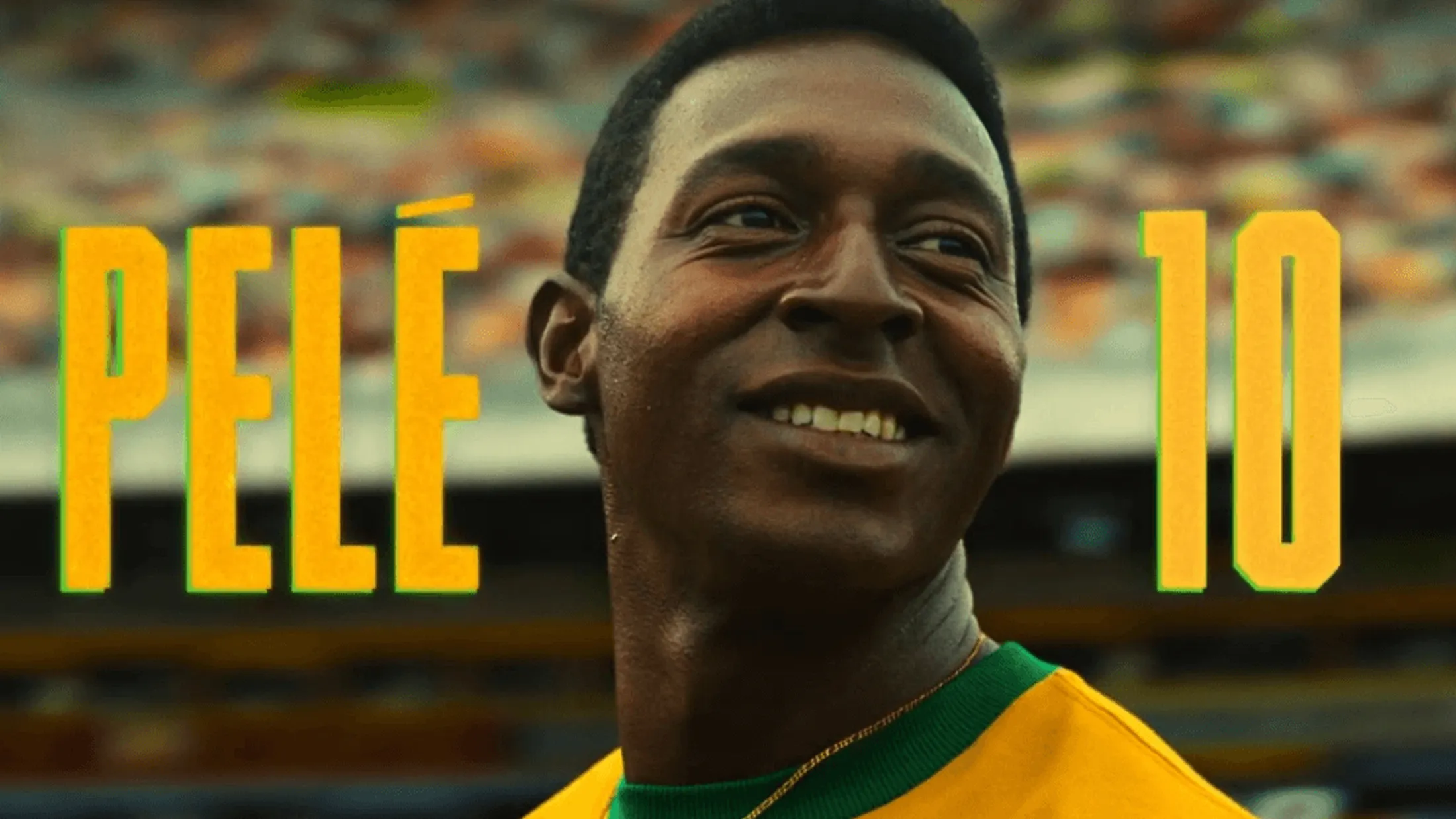 Lucas Agrícola interpretando o Pelé sorrindo com o texto "Pele 10" atrás