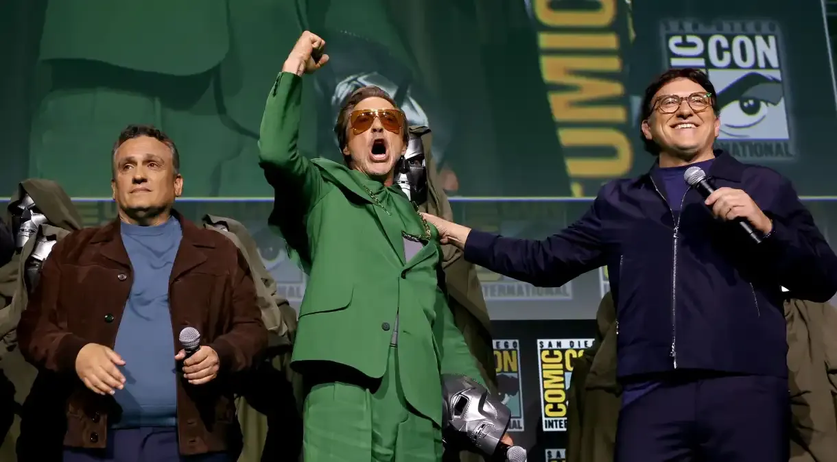 Robert Downey Jr. em painél da Comic-Con vestindo verde, punhos cerrados e óculos escuros.