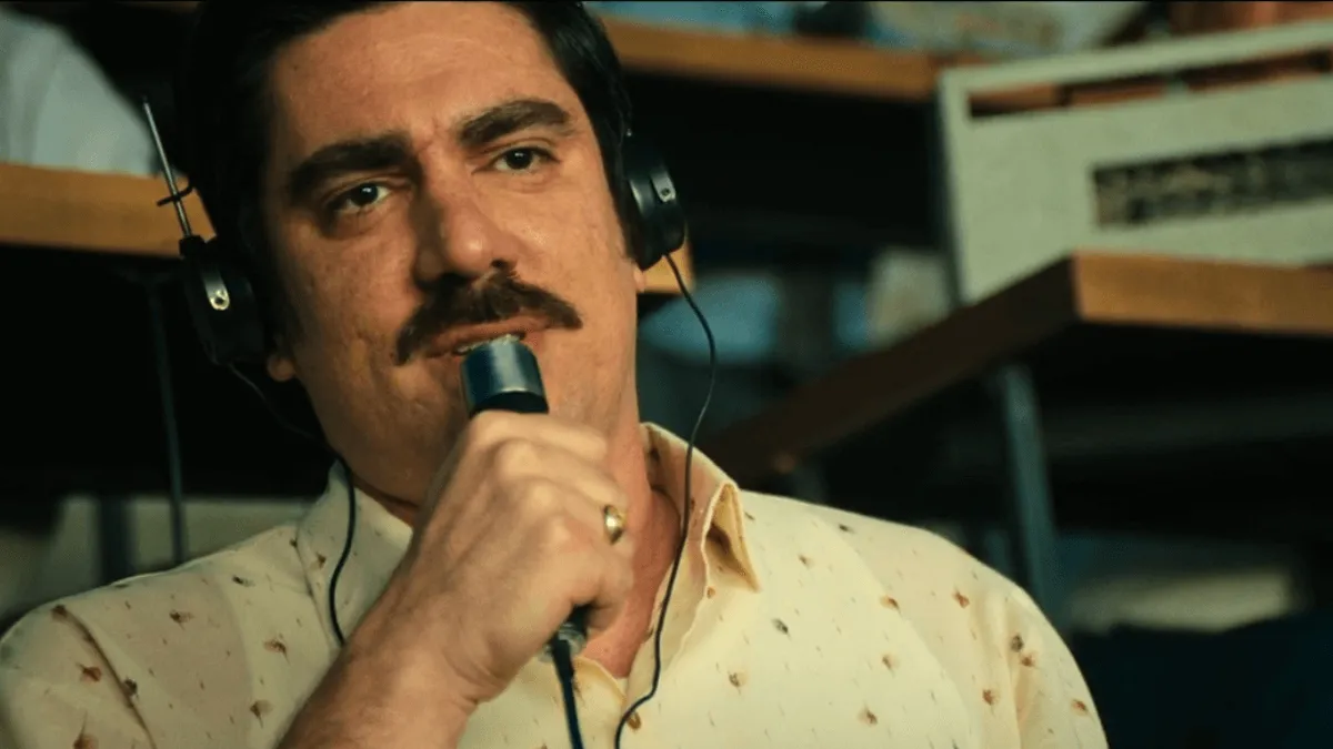 Marcelo Adnet como Eusébio Teixeira olhando para frente falando no microfone