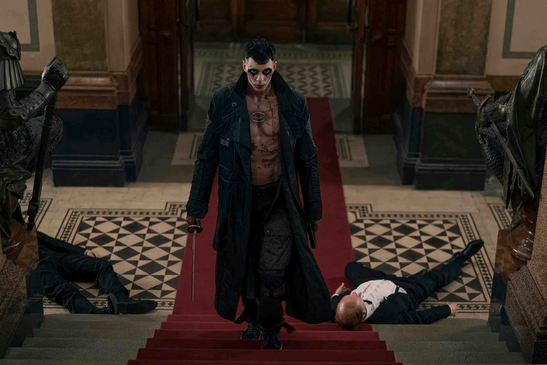 Personagem de O Corvo subindo uma escada com tapete vermelho e espada na mão.
