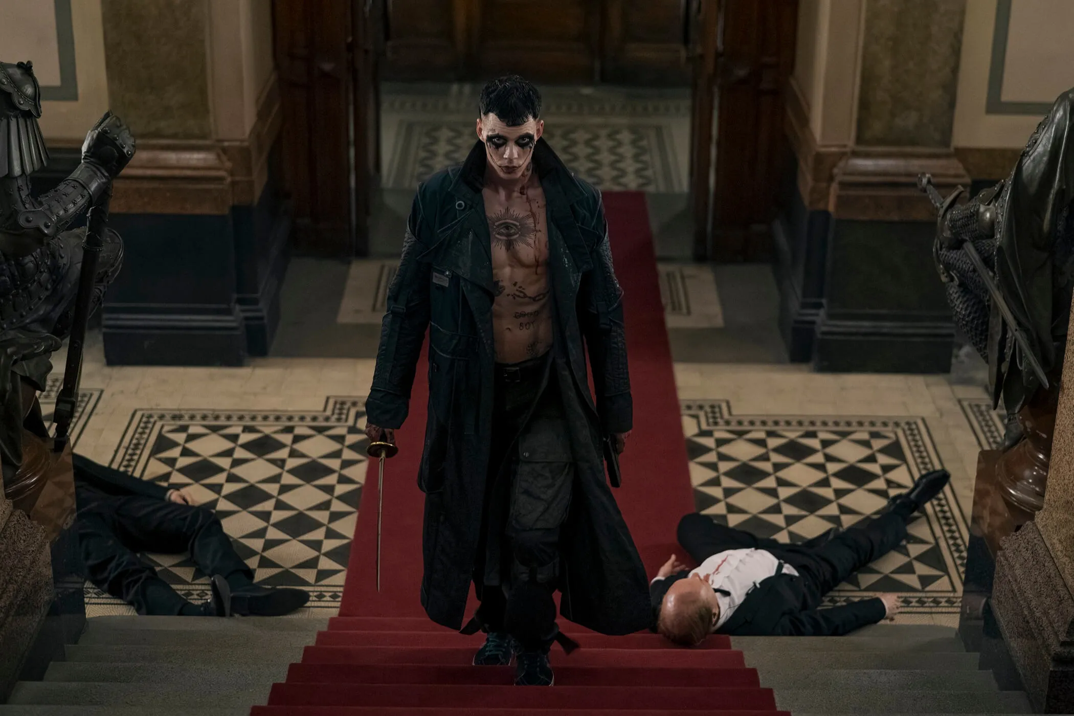 Personagem de O Corvo subindo uma escada com tapete vermelho e espada na mão.