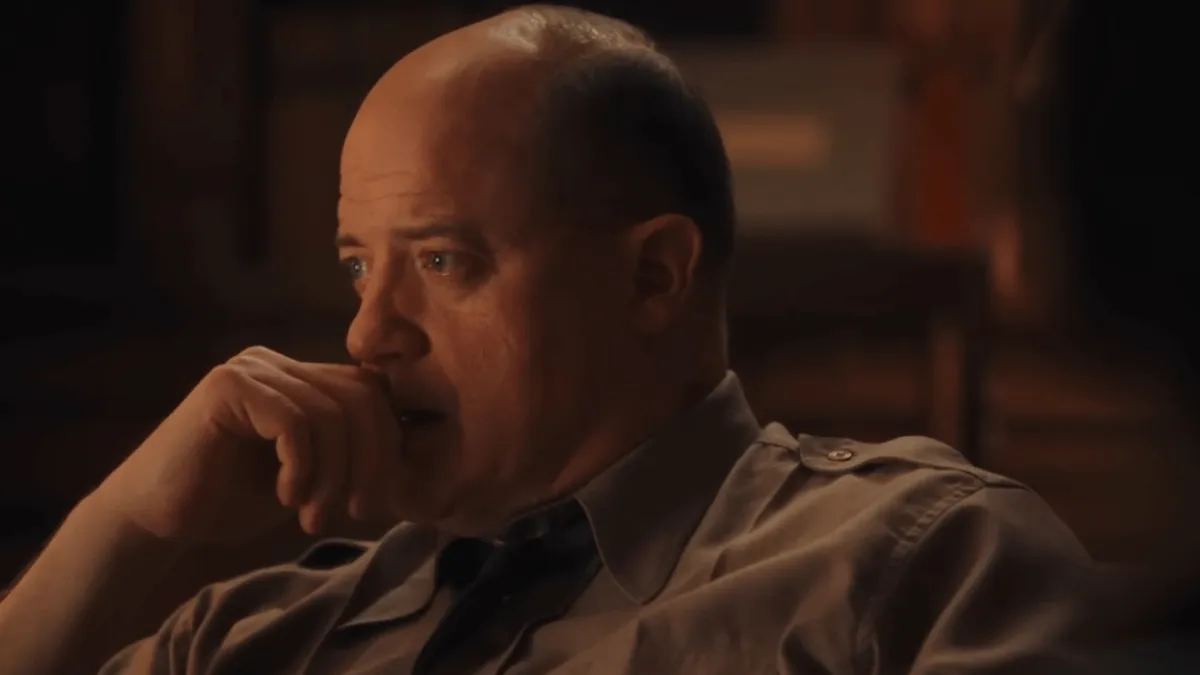 homem sentado olhando para a frente com a mão na boca