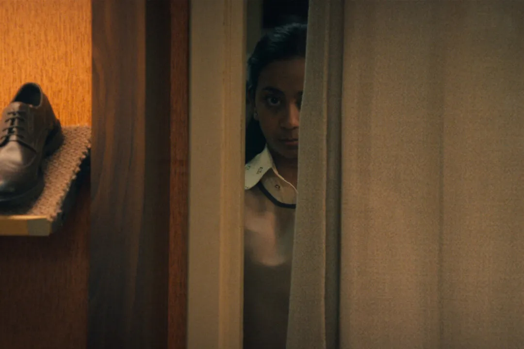 Imagem da nova temporada da série black mirror, ilustrando uma garota olhando entre a fresta de uma porta