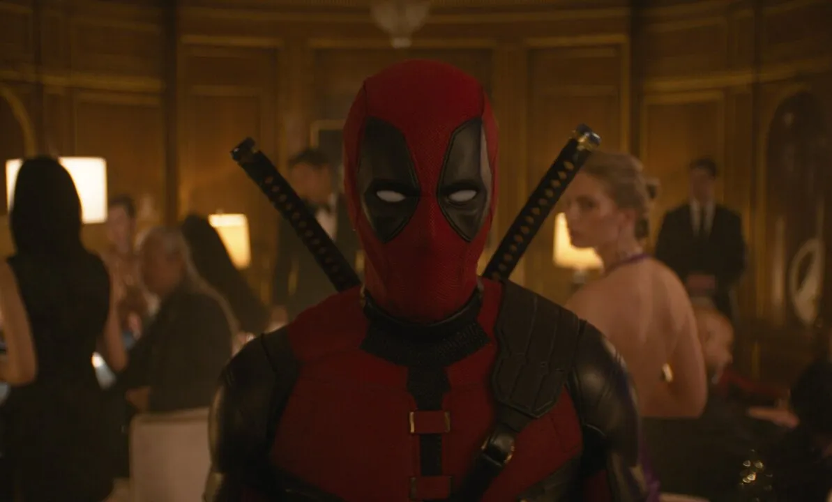 Personagem de Deadpool e Wolverine em meio a pessoas de uma festa.