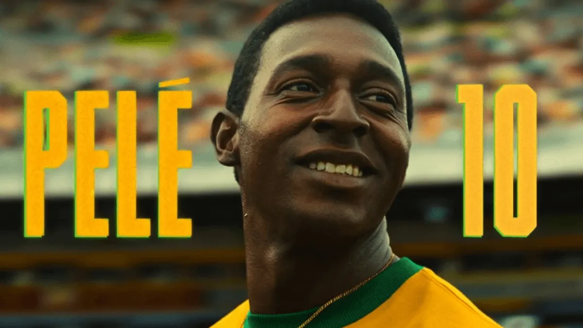 Lucas Agrícola interpretando o Pelé sorrindo com o texto "Pele 10" atrás