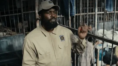 homem de casaco e boné com semblante de bravo levantando a mão