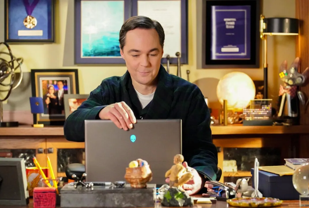 Homem sorrindo com as mãos no computador.