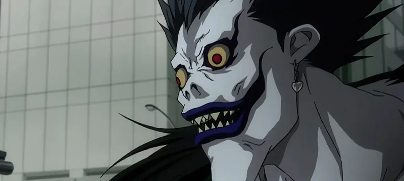 Ryuk, um dos shinigamis mais famosos dos animes olhando para frente com olhos grandiosos e dentes pontudos.