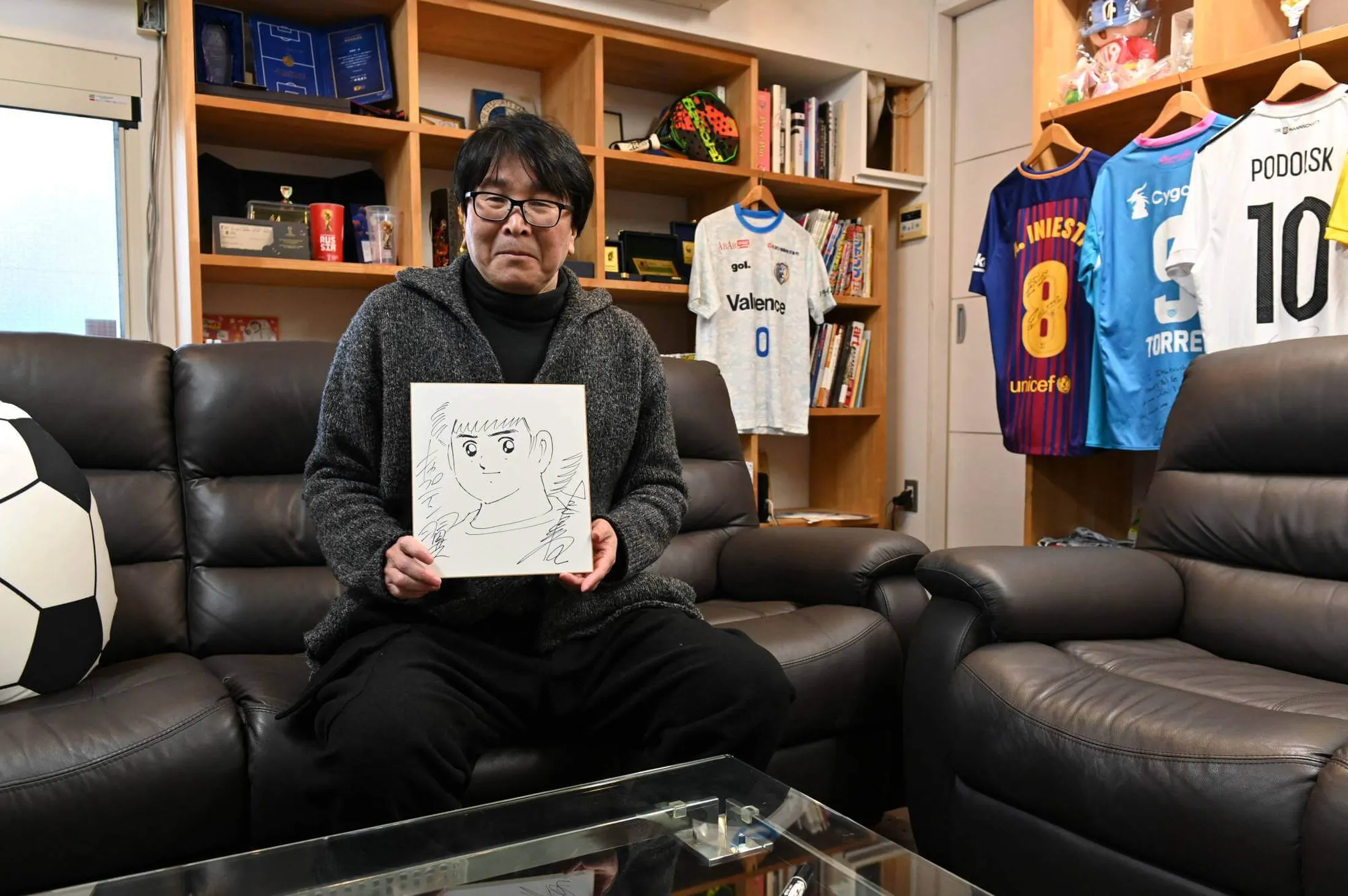 Yoichi Takahashi sentado segurando esboço de um de seus personagens