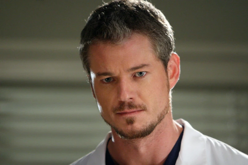 Personagem de Grey's Anatomy olhando para frente, com jaleco branco.