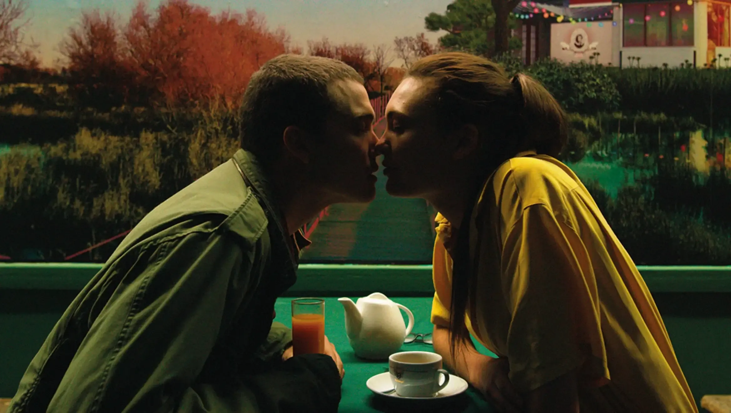 Personagens de um filme sobre orgasmo, com duas pessoas se beijando sentadas em uma mesa.