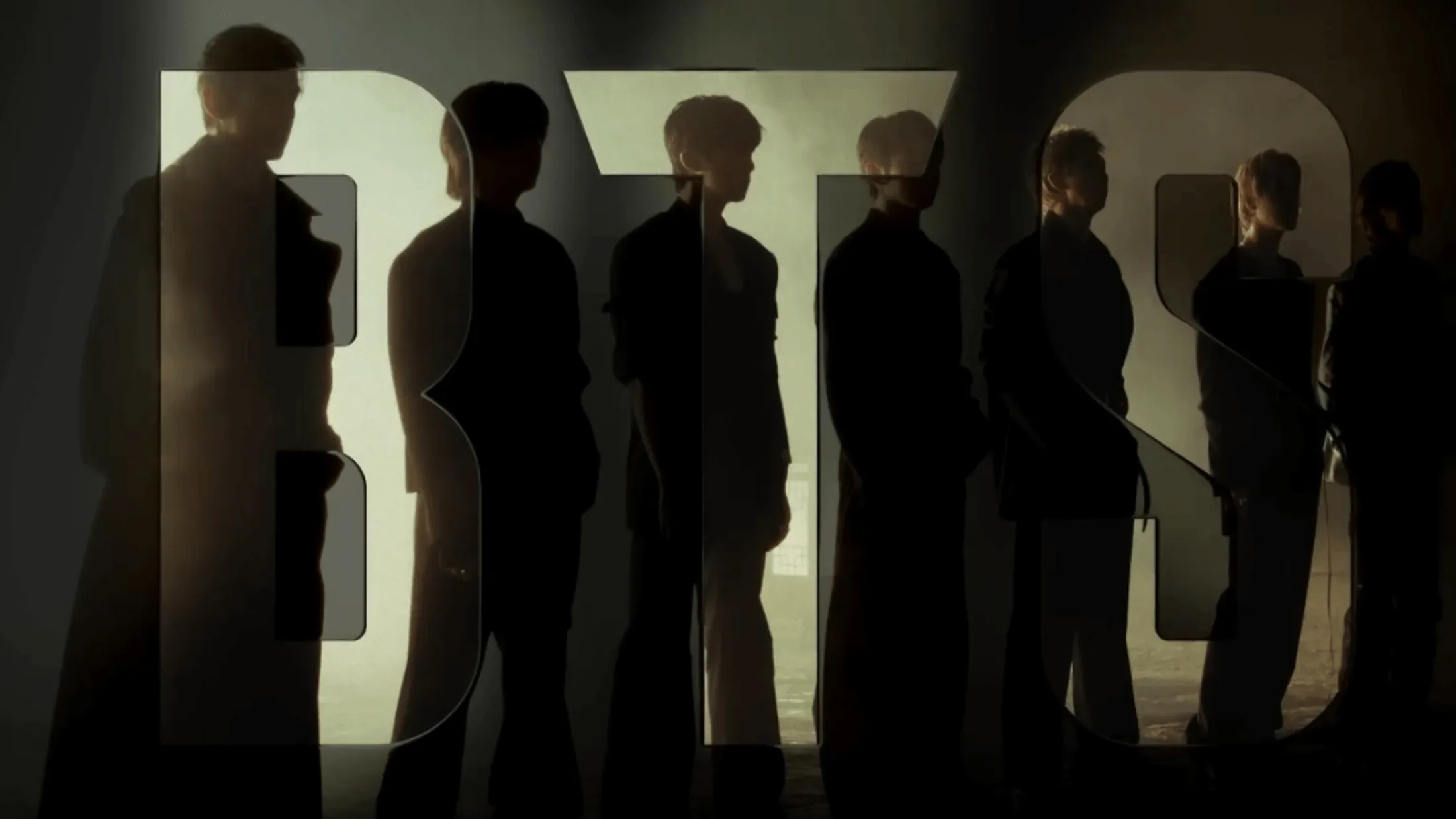 grupo BTS em pé no fundo da foto com o nome BTS na frente deles