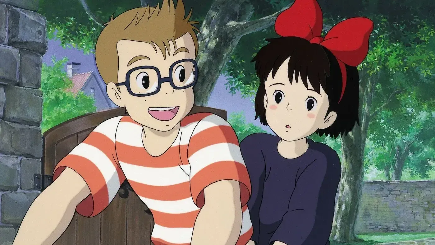 Animação com menino de óculos e camiseta listrada na frente sorridente e uma menina com laço grande vermelho na cabeça com expressão fria.