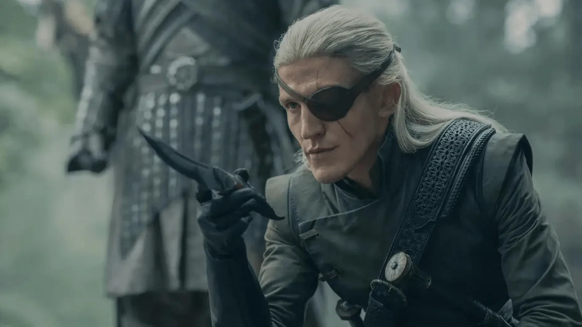 Aemond segurando uma adaga abaixado olhando para a frente