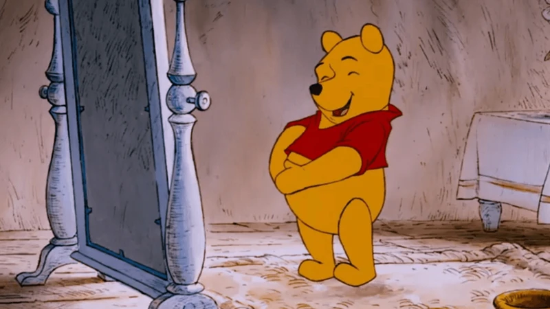 urso amarelo com blusa vermelha sorrindo e com as duas patas na barriga