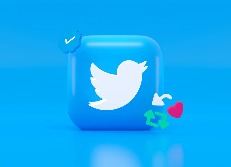 Logotipo do Twitter (silhueta de um pássaro virado para a direita) ) entalhado em uma espécie de pastilha azul com os ícones de funcionalidades flutuando ao redor da "pastilha"