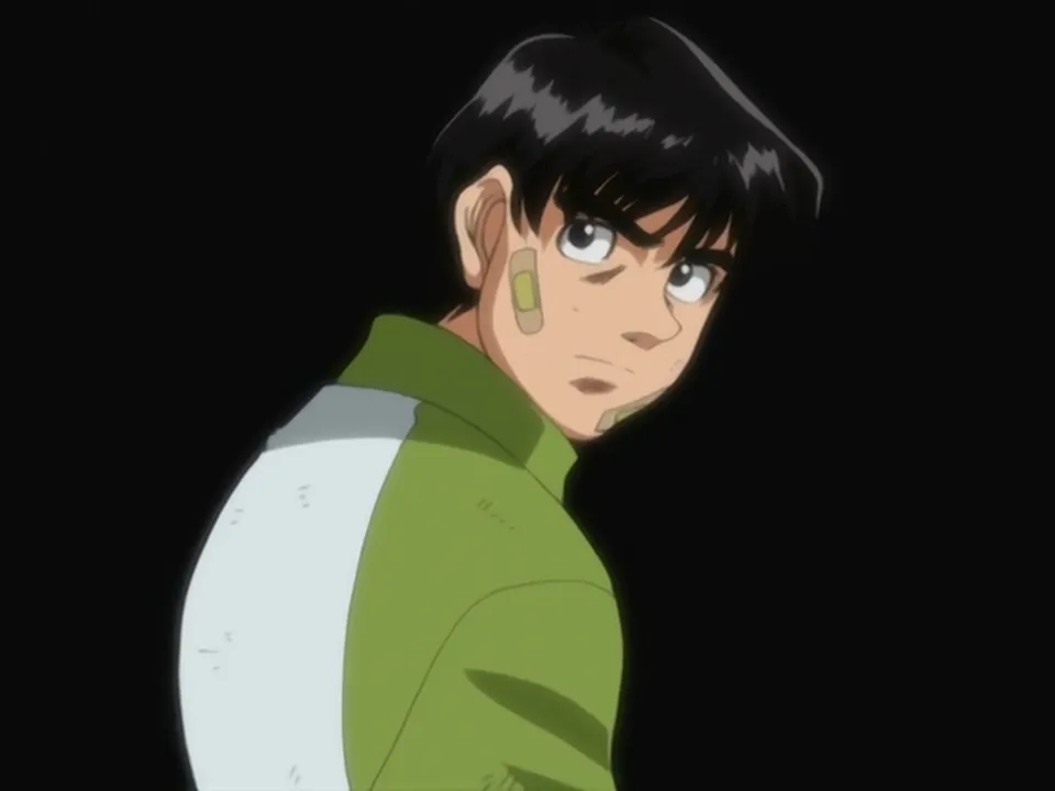 Kimura usando um casaco verde com uma parte branca, semelhante ao casaco de gohan do dragon ball super. O KImura está detacado, na frente de um fundo preto.
